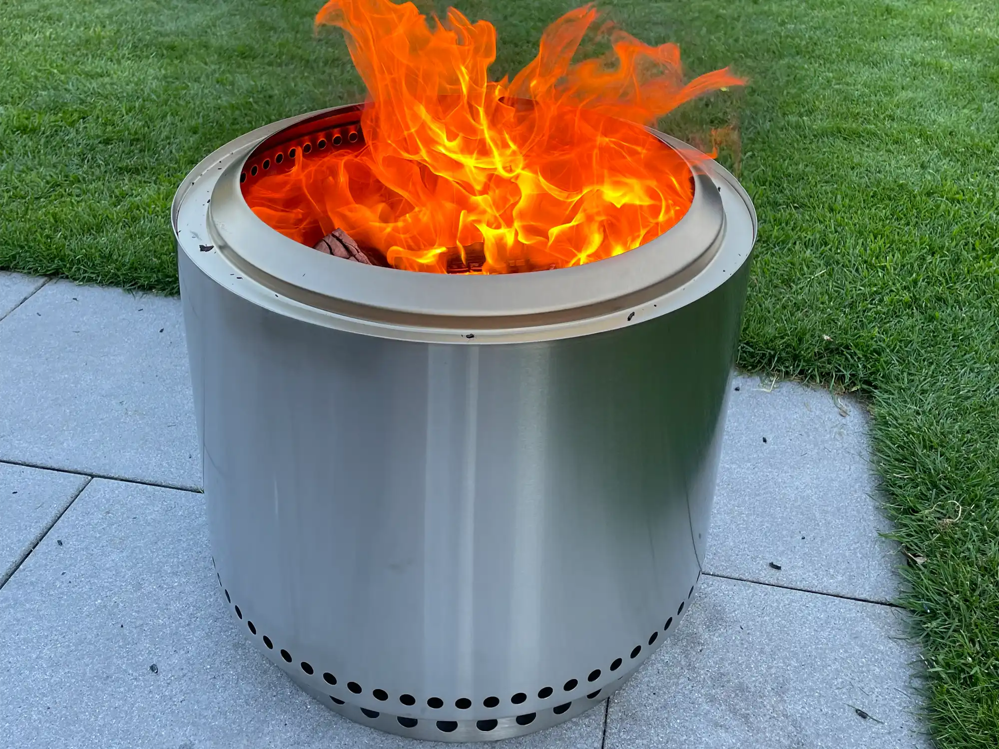 Brennende Solo Stove Bonfire auf Terrassenplatten neben dem Rasen